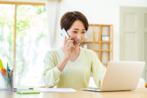 足立区でパソコン見ながら電話相談している女性